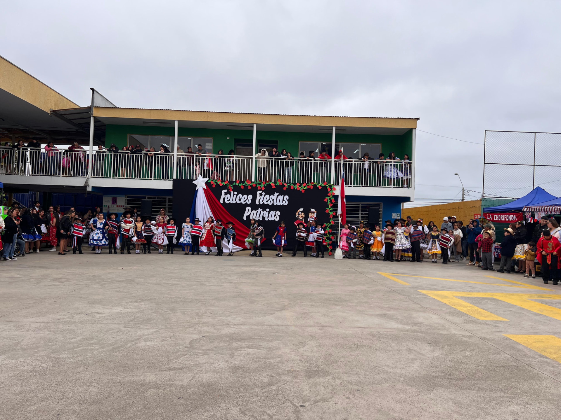 Acto de Fiestas Patrias en el patio del Colegio Rukalaf con la comunidad en los balcones